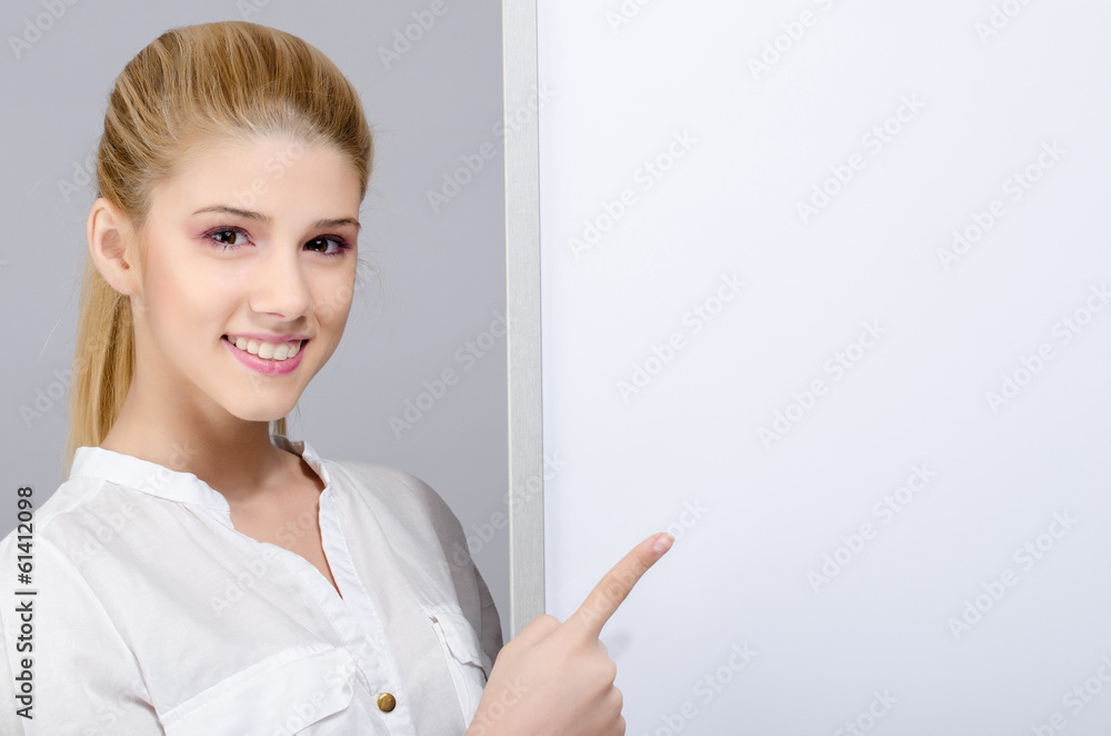 Young girl smiling and pointing to a white blank board. Young girl smiling and pointing to a white blank board.