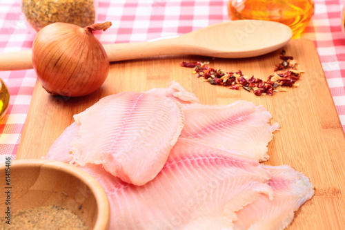 Raw fish tilapia on cutting board and spices