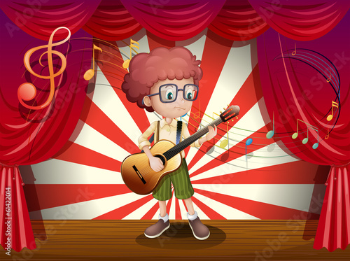 A young boy at the stage holding a guitar