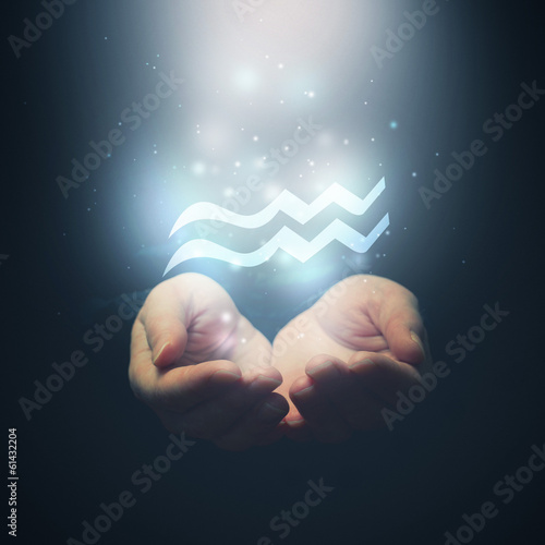 Female hands opening to light and holding zodiac sign for Aquari photo