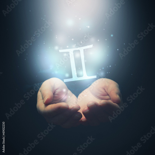Female hands opening to light and holding zodiac sign for Gemini