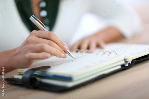 Closeup of woman's hand writing on agenda