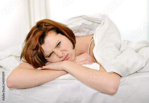 red hair woman on bed waking up with hangover and headache