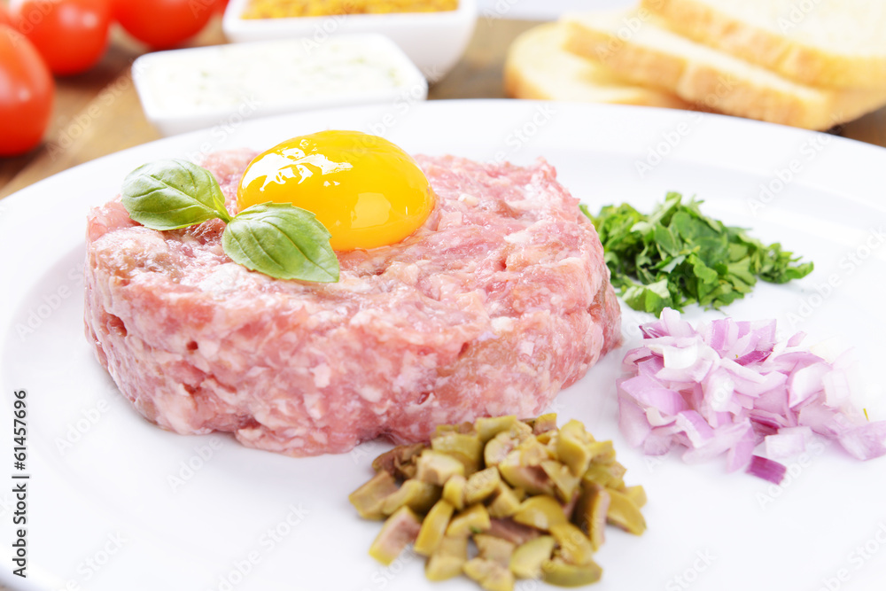 Delicious steak tartare with yolk on plate on table close-up Delicious steak tartare with yolk on plate on table close-up