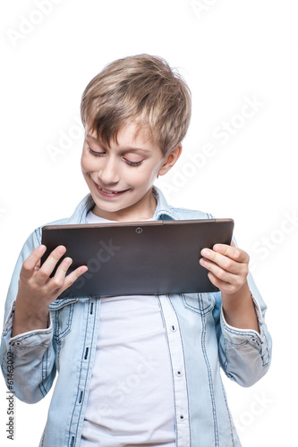 Cute stylish funny boy in a blue shirt playing at a tablet pc