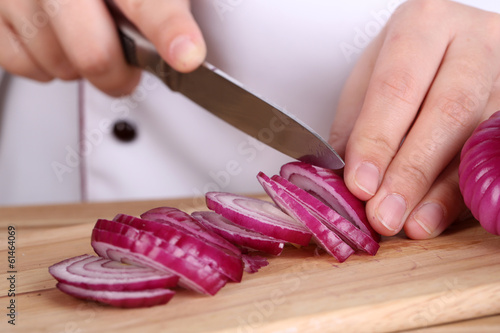 Female hands cutting bulb onion, close up