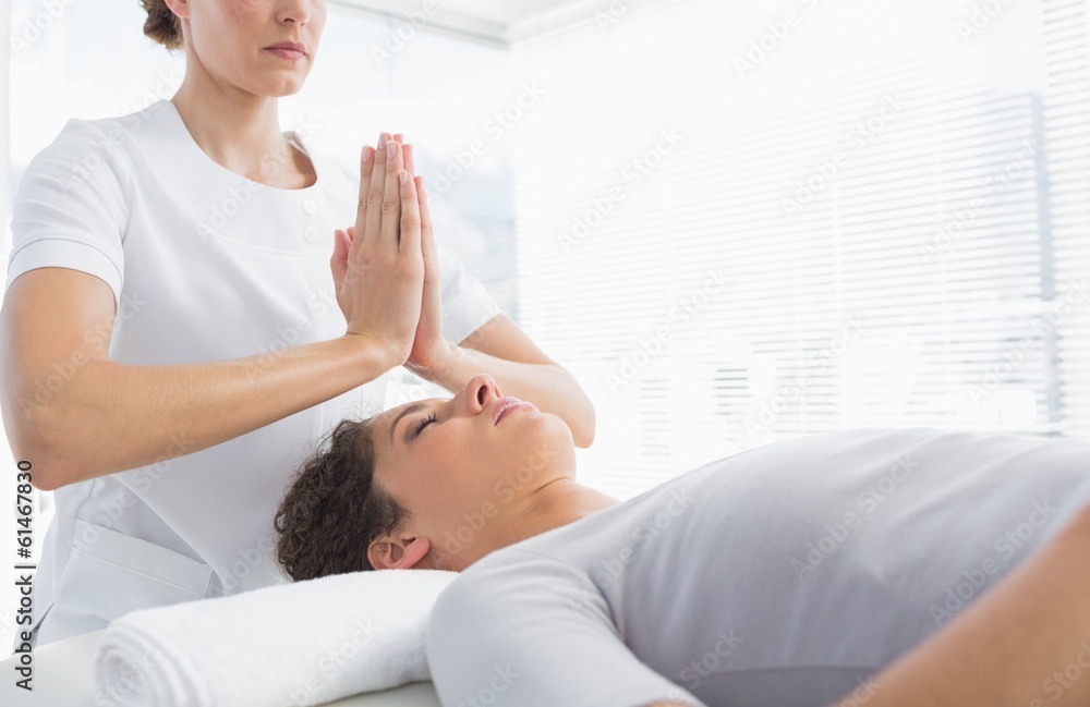 Therapist giving Reiki treatment to woman Therapist giving Reiki treatment to woman
