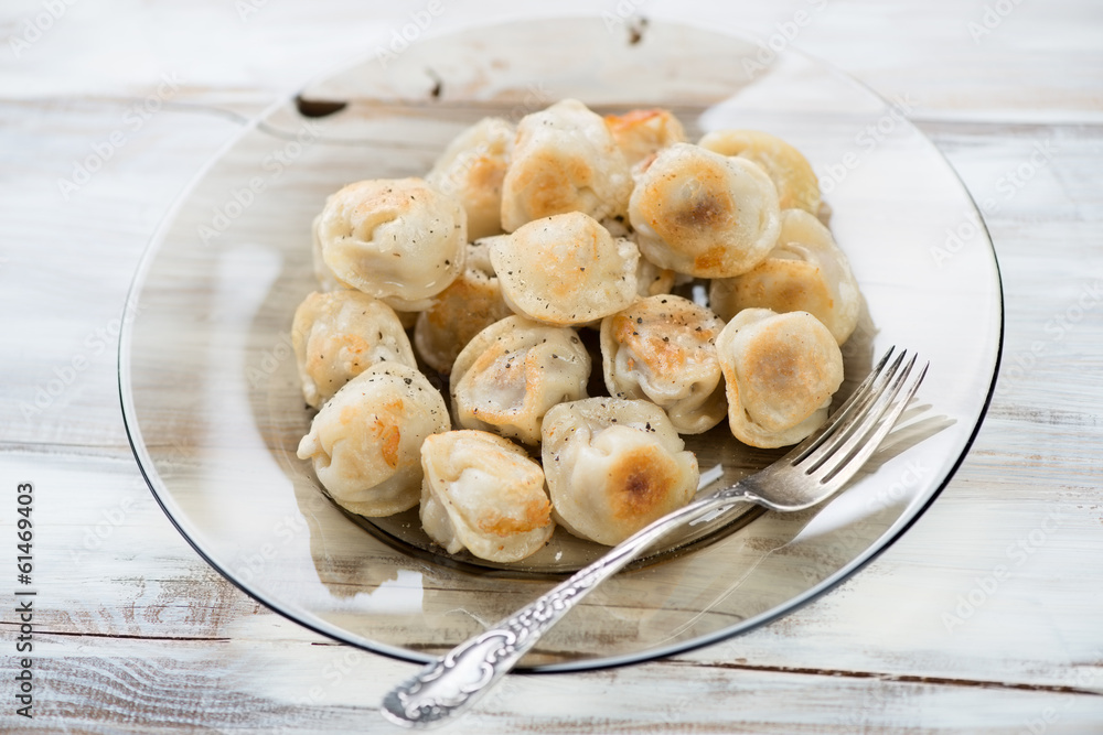 Plate with fried pelmeni or meat dumplings, horizontal shot Plate with fried pelmeni or meat dumplings, horizontal shot