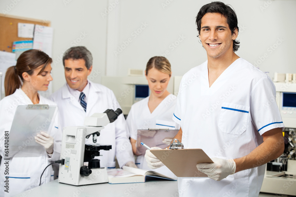 Male Scientist Holding Clipboard In Lab Male Scientist Holding Clipboard In Lab
