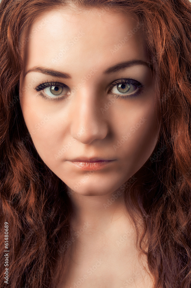 Closeup portrait of young woman with red hairs looking at camera