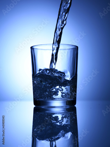 Pour water from pitcher into glass, on dark blue background