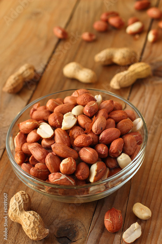 Raw peanuts or groundnuts on wooden table in glass bowl