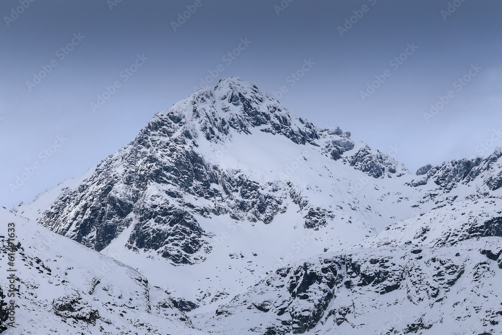 Severe mountains peaks covered by snow under dramatic sky