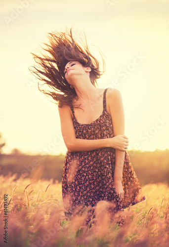 Romantic Model in Sun Dress in Golden Field at Sunset