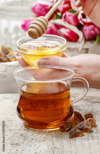 Pouring honey into glass of tea