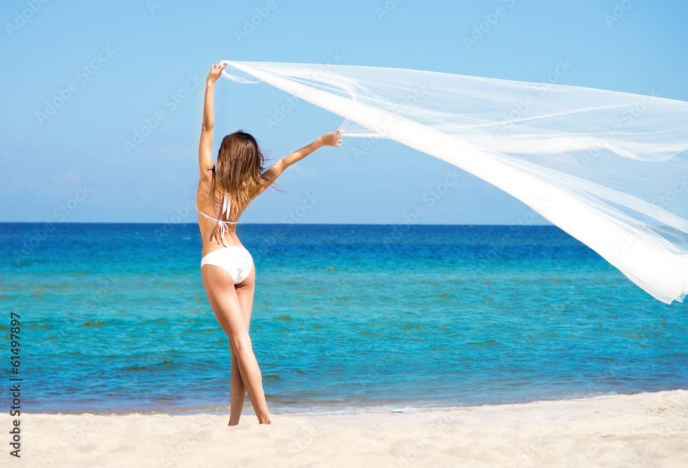 Obraz premium A beautiful woman in a swimsuit posing on the beach