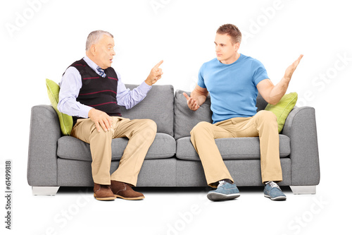 Two men arguing seated on a sofa