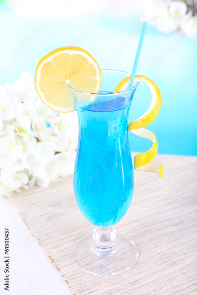 Glass of cocktail on table on light blue background Glass of cocktail on table on light blue background
