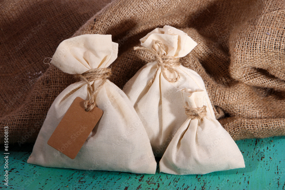 Sacks on color wooden table, on sackcloth background