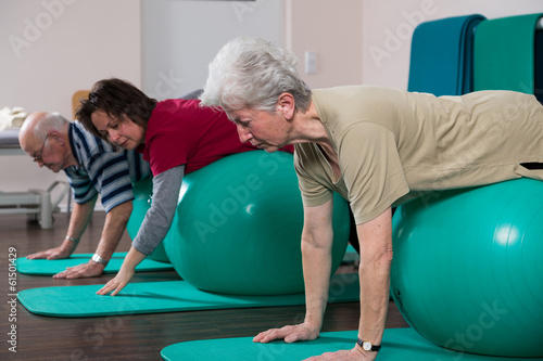 Physiotherapeutin übt mit Senioren auf Bällen