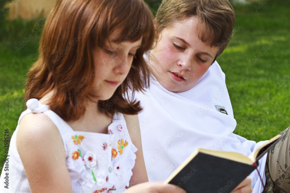 Teen.Portrait of cute kids reading books in natural environment Teen.Portrait of cute kids reading books in natural environment