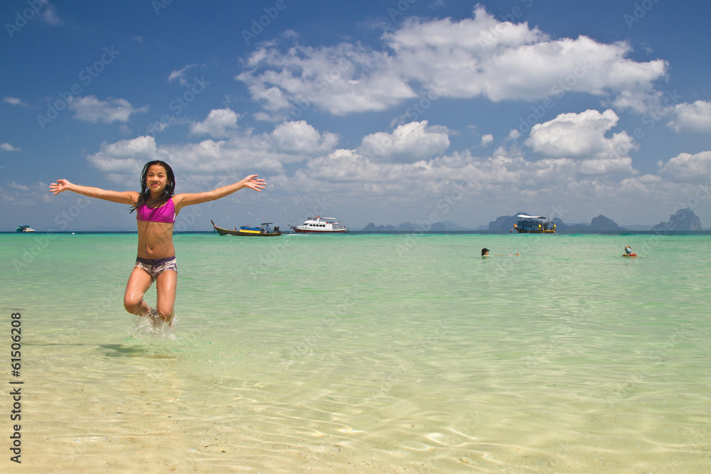 Girl jumping in the water at the beach of the Koh Ngai island Th