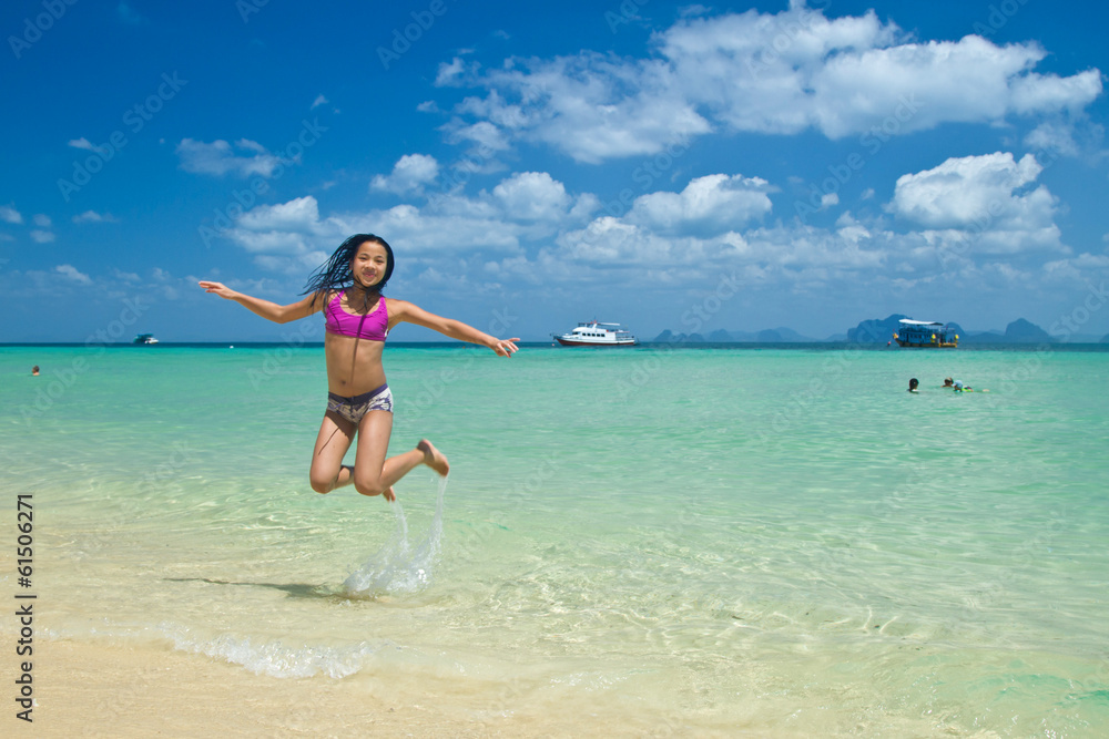 Girl jumping in the water at the beach of the Koh Ngai island Th Girl jumping in the water at the beach of the Koh Ngai island Th