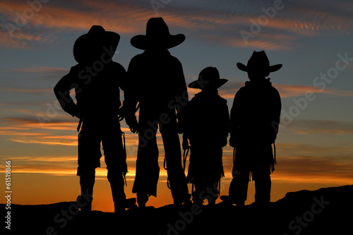 Beautiful silhouette of four young cowboys with a sunset backgro