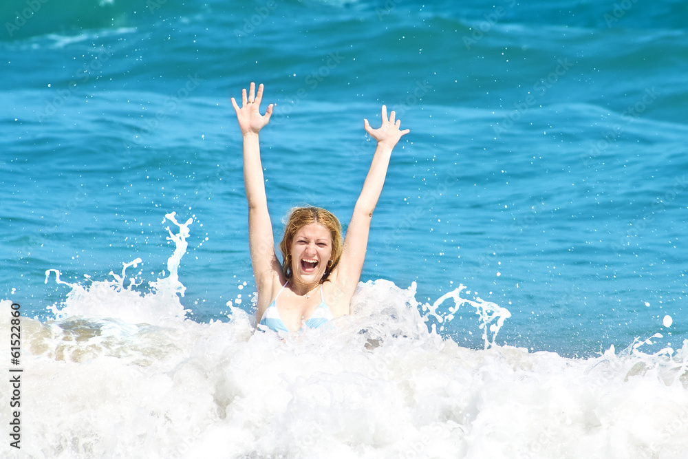 Young woman jumping in the waves on a tropical beach