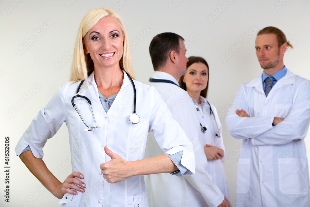 Doctor standing in front of coworkers on grey background Doctor standing in front of coworkers on grey background