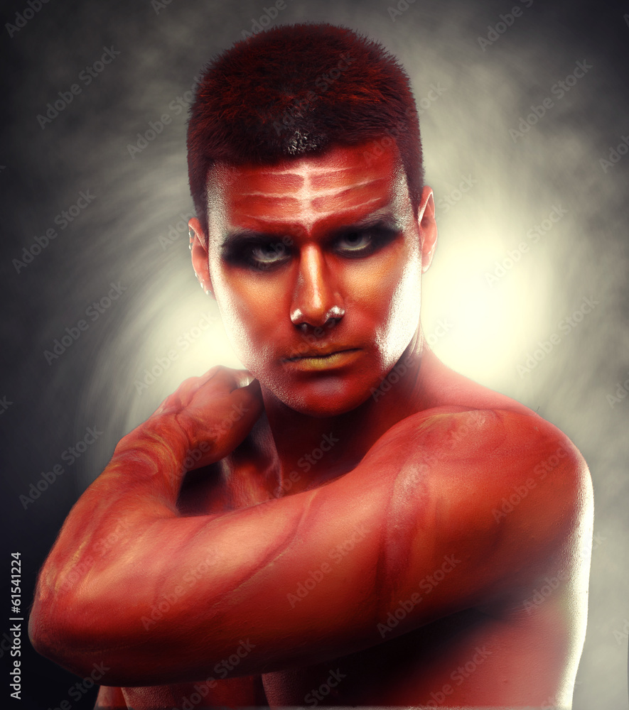 Portrait of a handsome young man in a red body painting