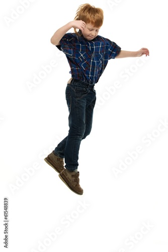Fototapeta Naklejka Na Ścianę i Meble -  Little funny redhead boy in shirt and jeans jumping