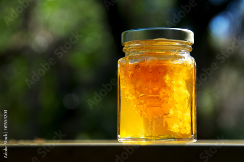 backlit jar of honey with honeycomb on wood