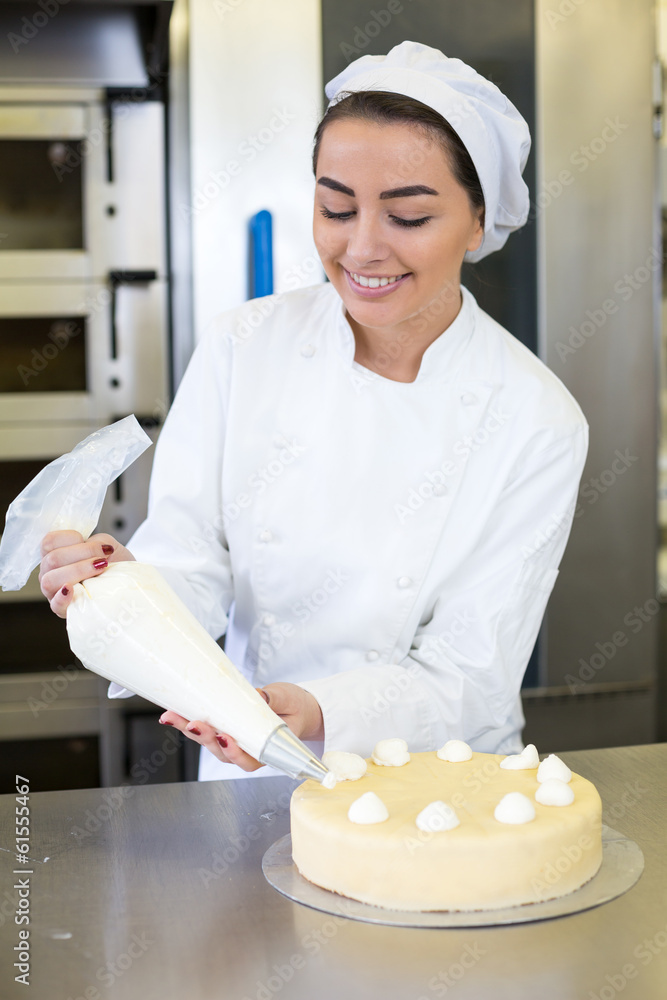 Baker prepares cake in bakehouse with whipped cream Baker prepares cake in bakehouse with whipped cream