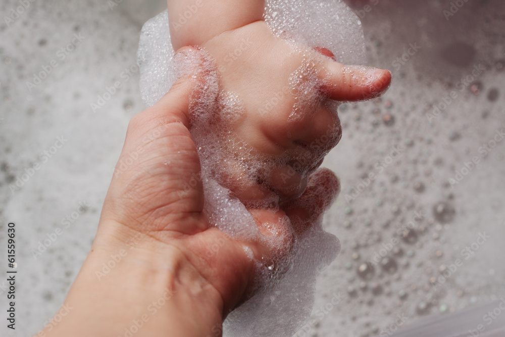 Fototapeta premium kid hand holding her mother's hand in the bath with foam