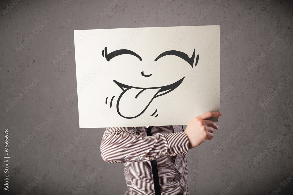 Businessman holding a paper with funny smiley face in front of h