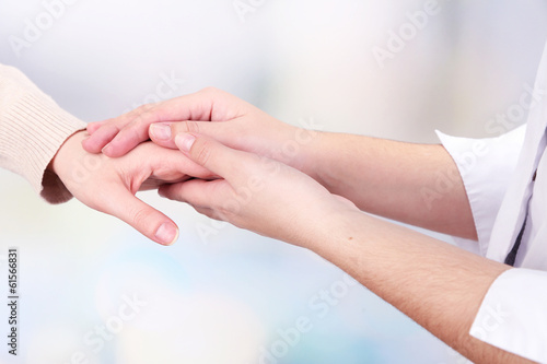 Medical doctor holding hand of patient  on light background