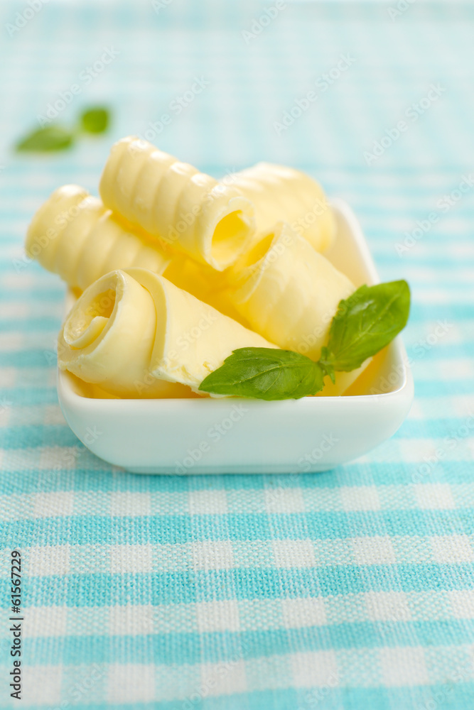 Curls of fresh butter with basil in bowl, on blue tablecloth Curls of fresh butter with basil in bowl, on blue tablecloth