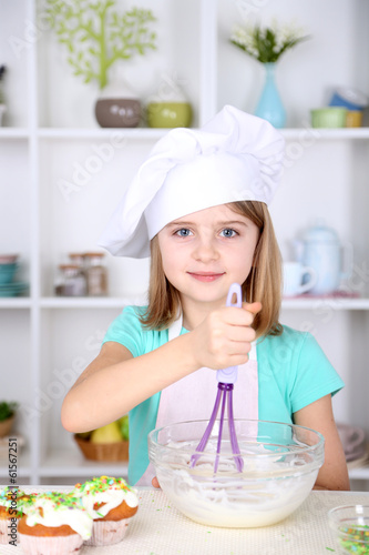Little girl eating cream in kitchen at home