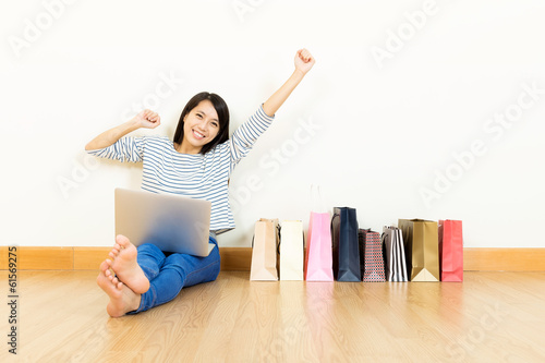 Asian woman online shopping at home with assorted paper bag