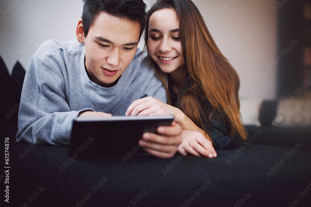 Relaxed teenage couple using digital tablet Relaxed teenage couple using digital tablet