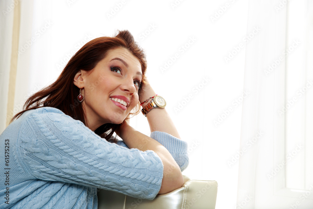Thoughtful woman sitting on the sofa and looking up at home Thoughtful woman sitting on the sofa and looking up at home