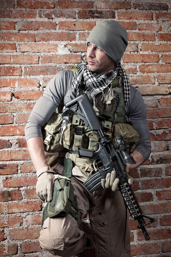 Portrait fo soldier with rifle on bricks background