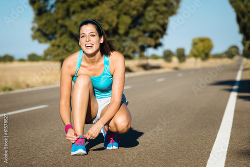 Woman tying sportshoes laces for running photo