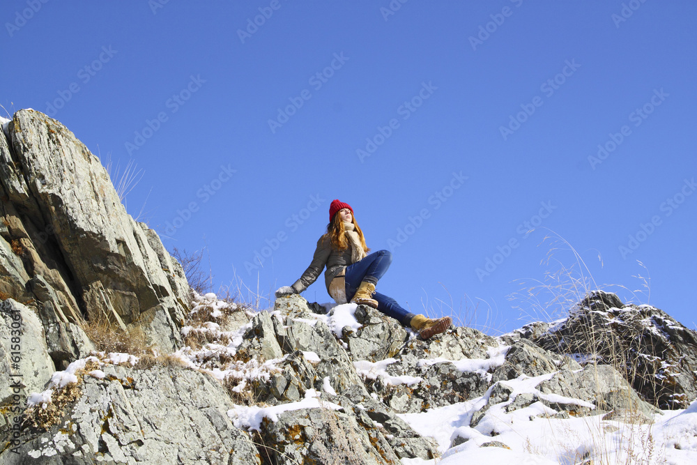 Young girl sitting on a rock and meditates