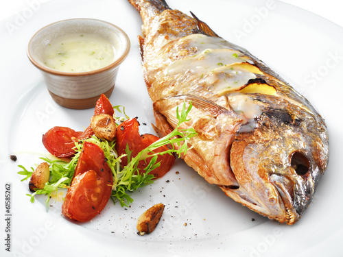 Grilled healthy dorado fish with vegetables on a round plate iso