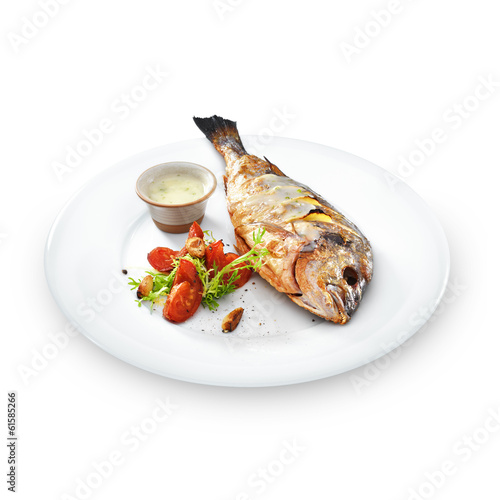 Grilled healthy dorado fish with vegetables on a round plate iso