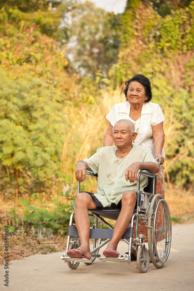 Senior woman pushing her disabled hasband on wheelchair Senior woman pushing her disabled hasband on wheelchair