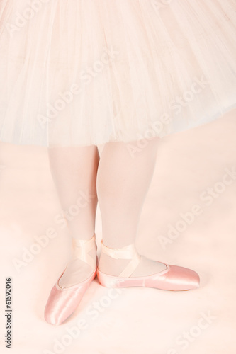 Ballet dancer standing on peach floor while dancing artistic con