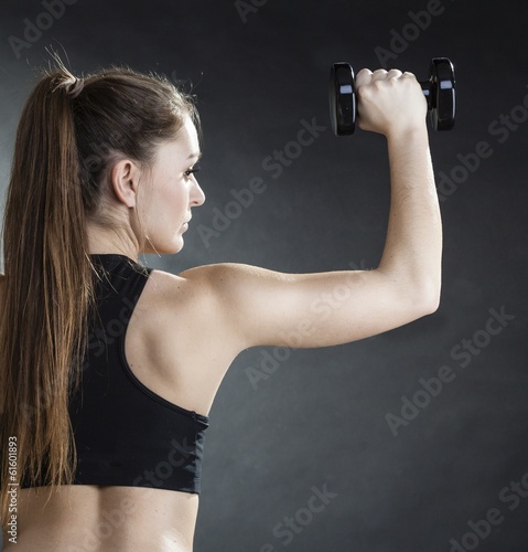 Fitness girl training shoulder muscles lifting dumbbells back